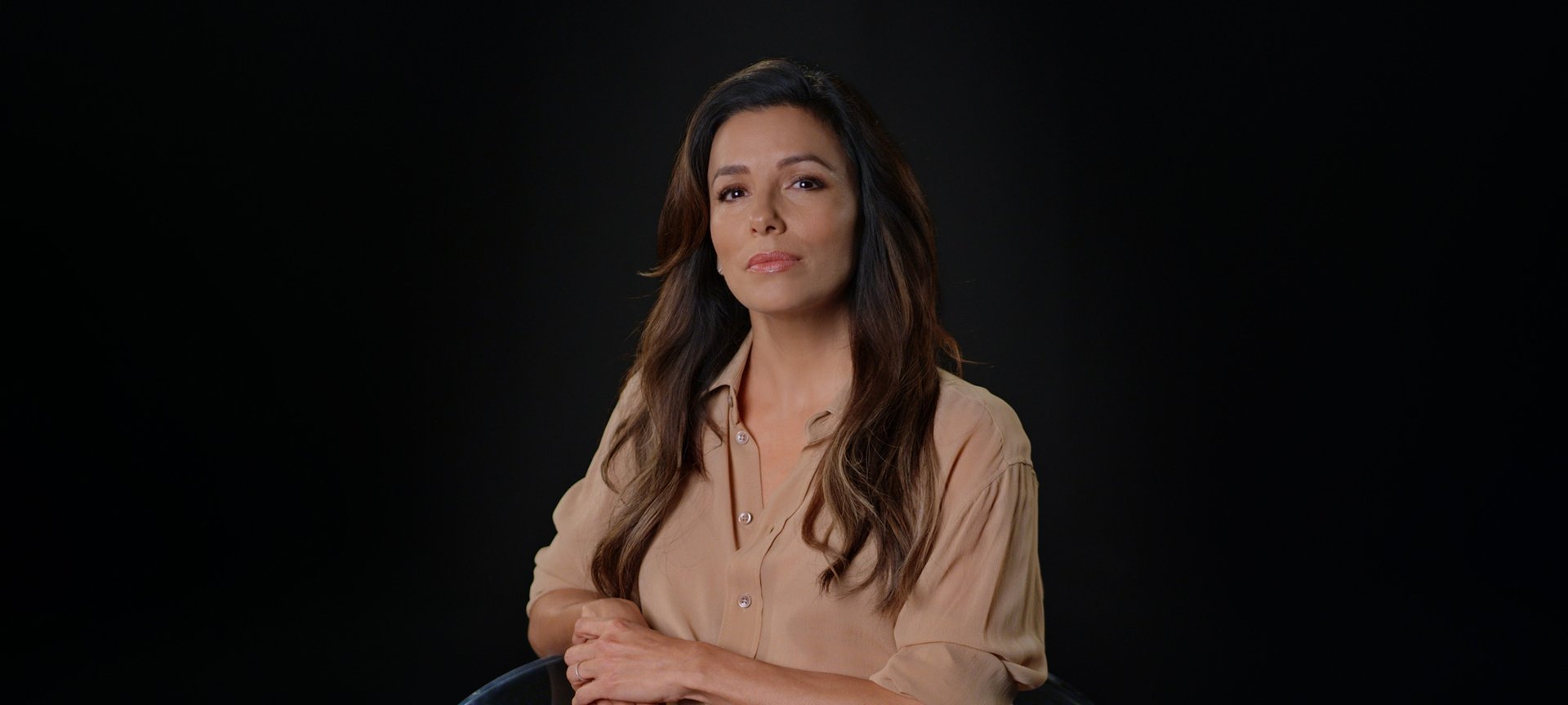 Portrait photo of Eva Longoria in front of black background.